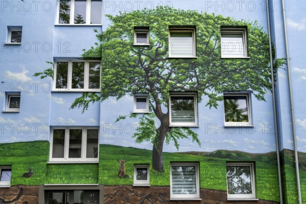 Residential buildings on Feldsieper Straße in Bochum, after an energy-efficient refurbishment, with facade insulation, the Bochumer Wohnstätten Wohnungsgenossenschaft had the buildings painted with a large mural by Dortmund graffiti artist Denis Klatt, it shows a bluethroat and a landscape with trees, life below ground and lots of sky on the entire facade, Bochum-Hamme, North Rhine-Westphalia, Germany