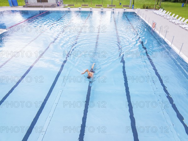 A swimmer moves in an almost empty swimming pool with clear lanes, Calw outdoor pool, Black Forest, Germany