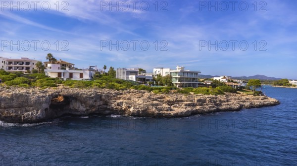 Stunning aerial view of the portocolom lighthouse and luxury villas perched on a rocky coastline in mallorca, spain, bathed in mediterranean sunlight