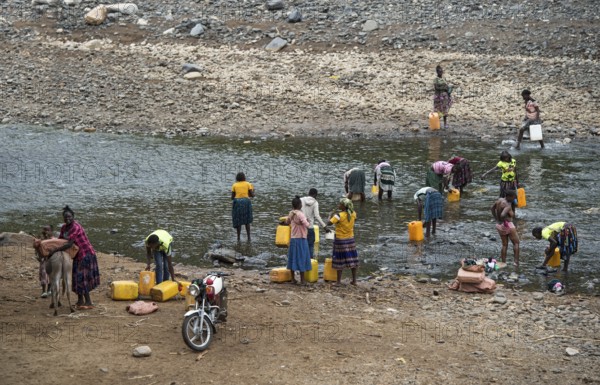 Women with plastic jerrycans fetching water and washing their bodies at a river near the road from Arba Minch to Konso, southern Ethiopia
