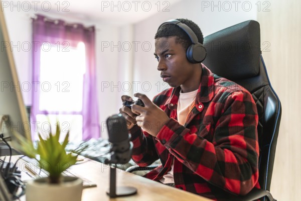 Young man focusing intently on playing video games while streaming live from a well equipped home setup, engaging with an online audience
