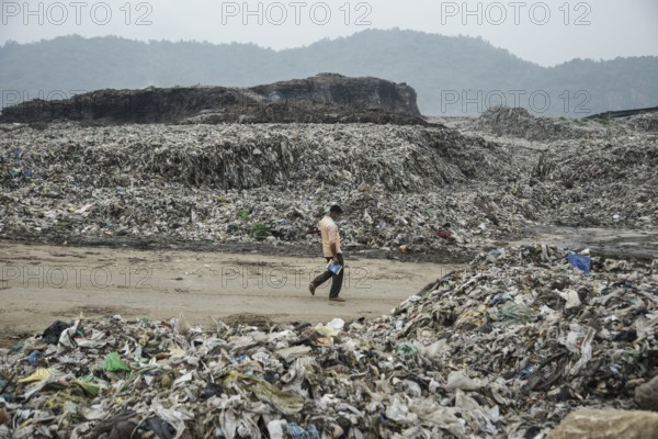 A person walking between garbage heap at a garbage dumpsite in the eve of World Environment Day, in Guwahati, Assam, India on 04 June 2022. World Environment Day is the biggest international day for the environment. Led by the United Nations Environment Programme (UNEP) on June 05 every year