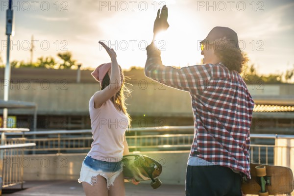 Two friends sharing a joyful high five after an exhilarating longboarding session, basking in the warm glow of a stunning sunset