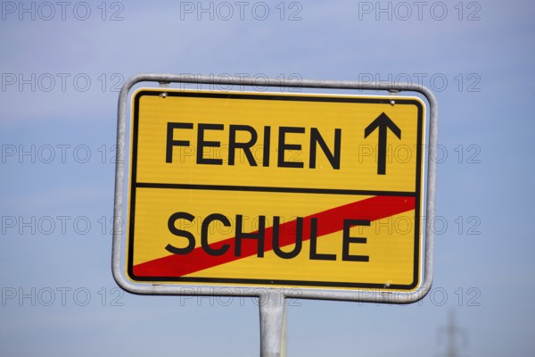 (Photomontage) Symbolic image summer holidays: Town exit sign with text HOLIDAYS and SCHOOL