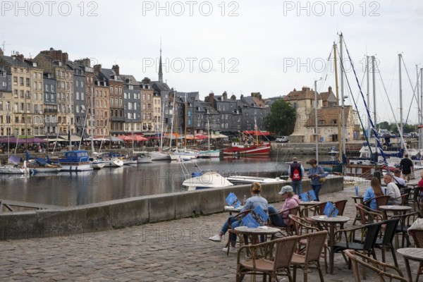Honfleur, Normandy, France - Boats on the Quai Sainte-Catherine and people in the street café in the old harbour, Vieux Bassin, in the picturesque harbour town of Honfleur at the mouth of the Seine