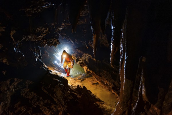 Speleologists climbing through a passage, Advent Cave, Schneizlreuth, Berchtesgadener Land, Upper Bavaria, Bavaria, Germany