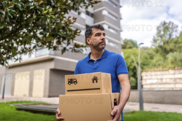 Handsome delivery man with boxes in his hands, working and walking along the city