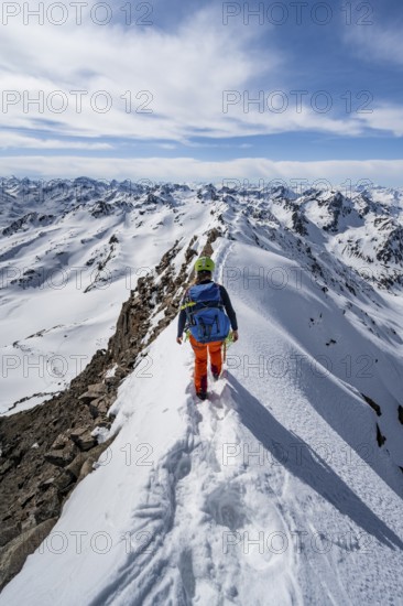 Mountaineer on a narrow mountain ridge in winter, summit of Piz Grialetsch, view of mountain panorama with snow, Grisons Haute Route, Albula Alps, Rhaetian Alps, Grisons, Switzerland