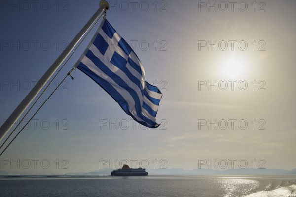 Greek flag waving, with a ship in the background and sunny sky, crossing Rhodes to Symi, ferry, Symi, Dodecanese, Greek Islands, Greece