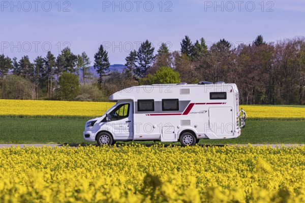 Country road with motorhome on the Swabian Alb with rape field in bloom. Erkenbrechtsweiler, Baden-Württemberg, Germany