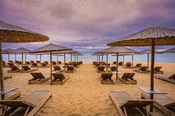 Deserted beach with bamboo umbrellas and sunbeds under a cloudy sky and calm sea, Golden Sands, Varna, Bulgaria
