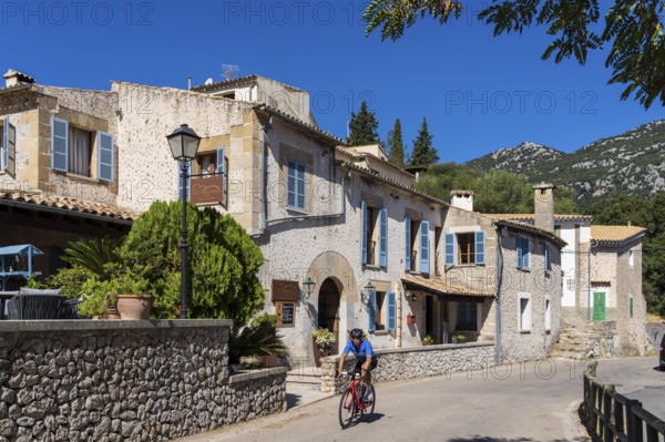 Cyclist crossing Orient village, Bunyola, Majorca, Balearic Islands, Spain