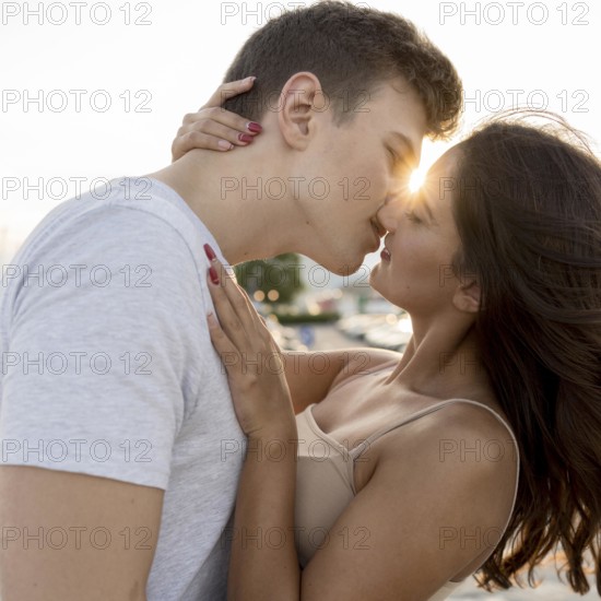 Side view couple kissing with sun peeking them