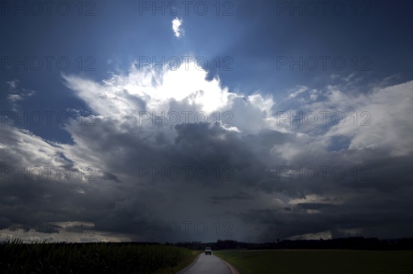 A lorry drives on a small country road directly towards a threatening thundercloud, doomsday atmosphere, Upper Bavaria, Bavaria, Germany