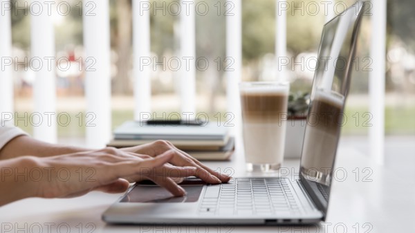Side view businesswoman working with laptop having coffee