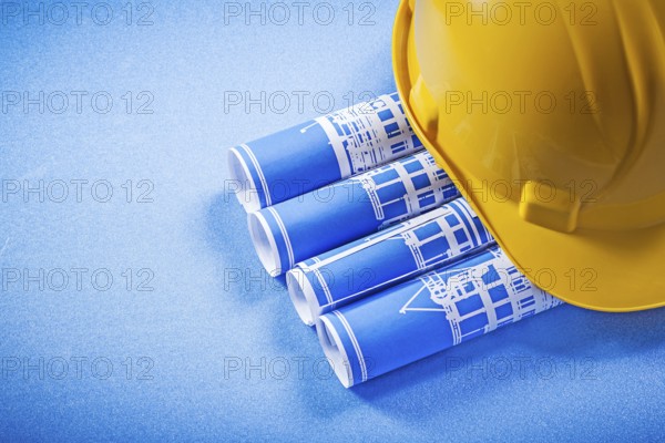 Rolled up construction plans hard hat on blue background