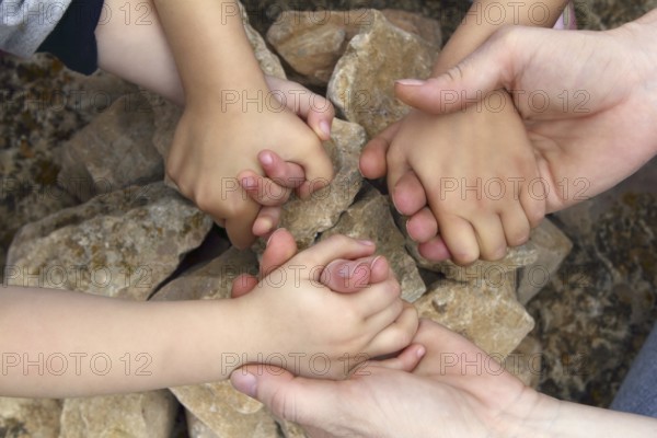 Adult and chilcren holding hands around stone circle wishing desire