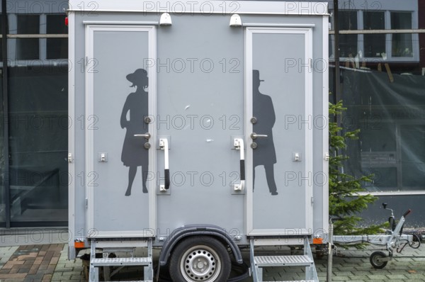 Modern portable toilet trailer with separate entrances for men and women, featuring elegant victorian silhouettes