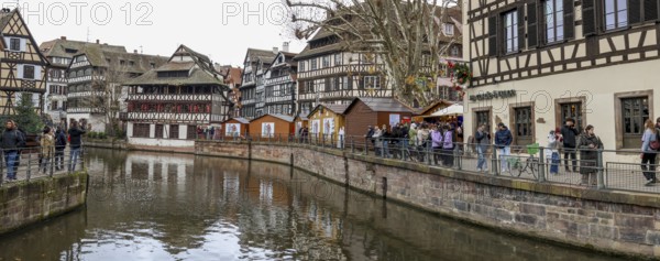 Panoramic photo of the river Ill with strolling tourists, surrounded by half-timbered houses in the old town, La Petite France, Strasbourg, Alsace, Département Bas-Rhin, France