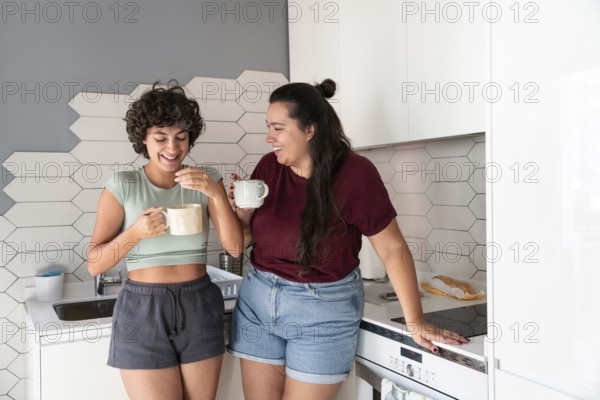 A lesbian couple stands in a cozy kitchen, sipping morning coffee. The modern decor and soft lighting create a warm atmosphere, perfect for a pleasant start to the day