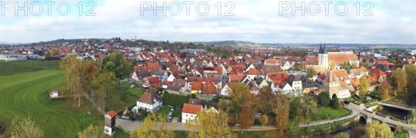 This aerial photo shows the picturesque town of Herrieden. At the centre are the red roofs of the closely spaced buildings, which represent the typical townscape of a small Bavarian town. The autumn colours of nature lend the image a warm and inviting atmosphere, while the view beyond the town reveals a beautiful landscape. Herrieden, Middle Franconia, Bavaria, Germany