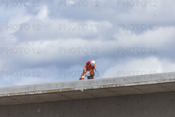 Following the partial collapse of the Carola Bridge, demolition work is continuing. A new change of technology, in which the bridge sections are to be channelled into folded beds, is currently being prepared by backfilling work. A worker secured with a rope is working on the markings on the bridge remains, Dresden, Saxony, Germany