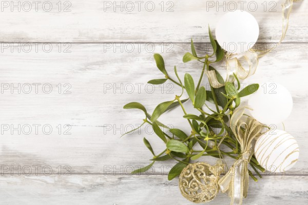 Branch of Mistletoe with ribbon and christmas balls on wooden background with copyspace. Christmas background