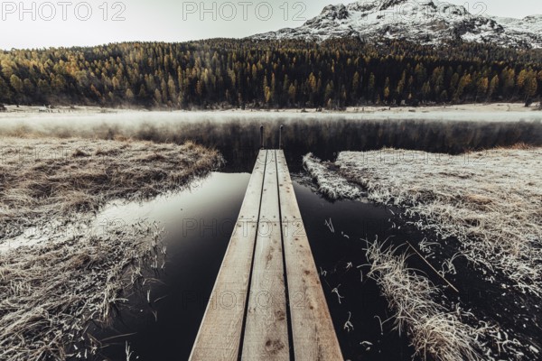 Lake Staz near Sankt Moritz in the Engadin in Switzerland. Morning atmosphere with fog in autumn. Water reflection and snow-covered mountains in the background