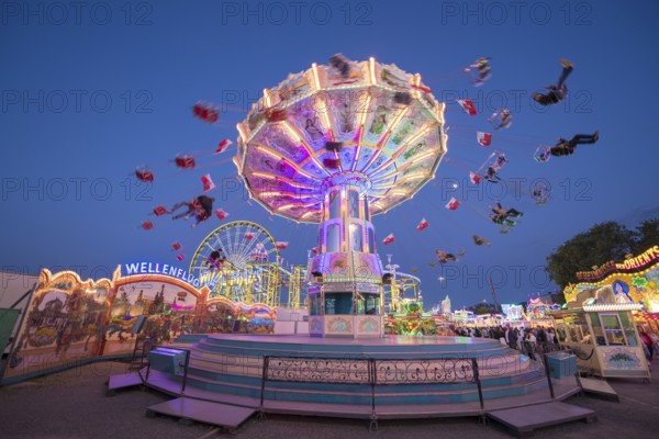 An illuminated chain carousel turns at a fairground at night, chain carousel, spring festival, Cannstatter Wellenflug, blue hour, Cannstatter Wasen, Bad Cannstatt, Stuttgart, Baden-Württemberg, Germany