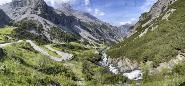 Panoramic view of south ramp south ascent to descent from Alpine pass Stelvio Pass, right foreground Cascata del Braulio waterfall, Valdidentro, Lombardy, Italy