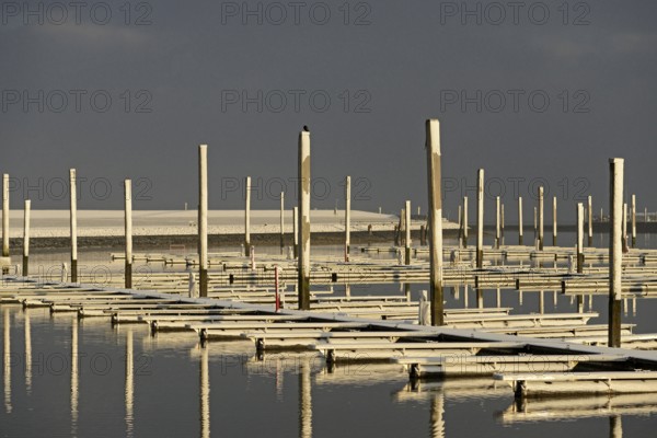Winter day, onset of winter, morning sun shining on the snow-covered jetties in the marina, North Sea, Norddeich, Lower Saxony, Germany