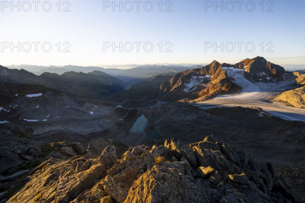 Picturesque high mountain landscape at sunrise with alpenglow, blue glacial lakes, glaciers and rocky mountain peaks in the morning light, view at the Becher on mountain peak Königshofspitz with glacier Übeltalferner, Stubai Alps, South Tyrol, Italy