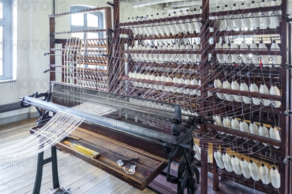 Bramsche, Lower Saxony, Germany, weaving machine, loom, in a textile factory, numerous spools of thread and visible mechanisms in the clothmaking museum