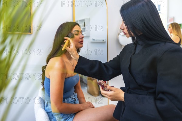 Professional makeup artist applying foundation on a client's face using a brush, enhancing her beauty in a salon environment