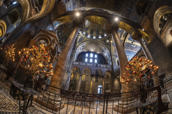 Wide angle view of the illuminated interior of saint mark's basilica in venice, italy, showcasing its ornate candelabras, mosaic art, and architectural details
