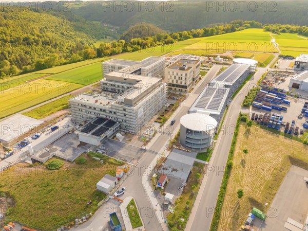 Industrial building complex in green surroundings with streets and hills, construction of the new hospital health campus Calw, Germany