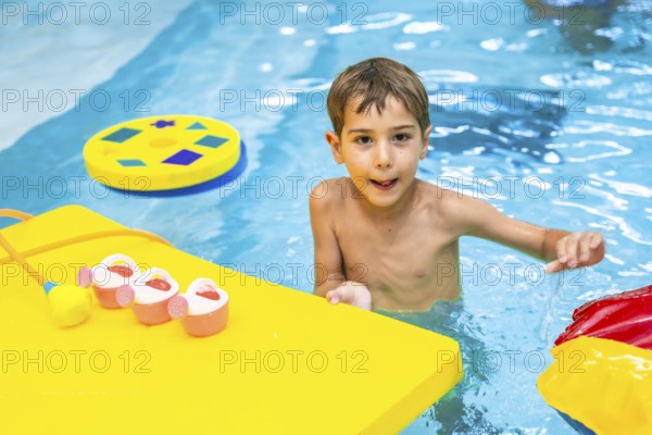Happy boy enjoying playful moments with colorful floating toys in a swimming pool, embracing the joy of summer fun and leisure activities
