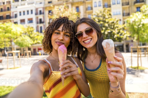 Two happy female friends enjoying ice cream cones on a sunny day in the city, taking a selfie to capture the moment