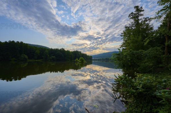 An impressive sky with clouds over a quiet, reflecting river at sunrise, summer, Grünenwört, Wertheim, Main, Main-Tauber-Kreis, Baden-Württemberg, Germany