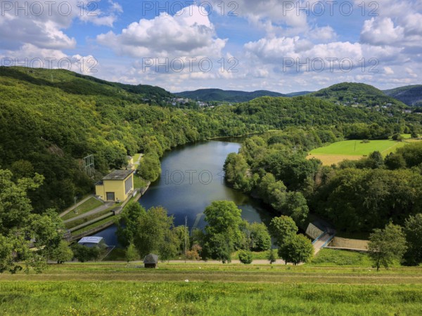 Dam wall with river amidst lush green hills under a cloudy sky, summer, Rursee, Rurtalsperre, Simmerath, Eifel National Park, North Rhine-Westphalia, Germany