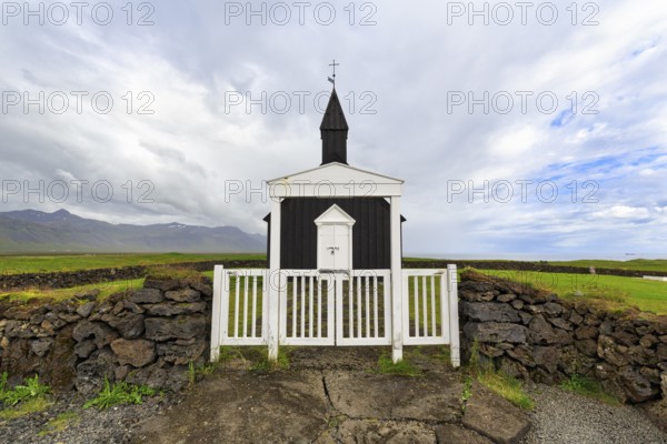 Traditional black church with white wooden door and stone wall, wooden church Budakirkja, Búðir, Budir, Snaefellsnes Peninsula, Iceland