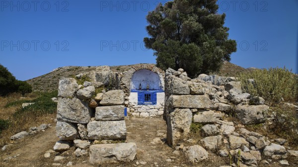 Stone chapel with blue façade amidst ancient ruins, embedded in lush vegetation, Artemis Temple, Artemis, Diana, goddess of the hunt, altar. Church, tower, near the airport in the north of the island, Leros, Dodecanese, Greek Islands, Greece