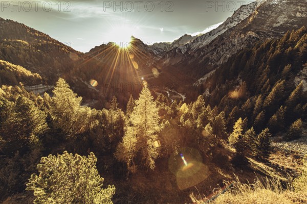 Woman sitting thoughtfully at a feslen at autumn atmosphere during sunset in the Swiss Alps in the Engadine. Photographed from the village of Maloja on the Maloja Pass
