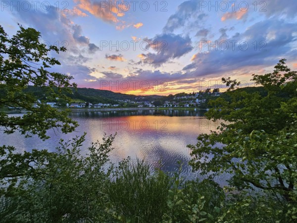 Colourful sunset over a calm lake, surrounded by trees and reflecting clouds in the sky, summer, Rursee, Rurtalsperre, Rurberg, Simmerath, Eifel National Park, North Rhine-Westphalia, Germany