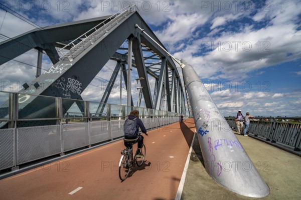 Cycle and pedestrian bridge Snelbinder Brug, over the river Waal near Nijmegen, was added to the existing railway bridge, fast cycle path connection from the city centre of Nijmegen and the new housing estates in the Waalsprong district, Netherlands