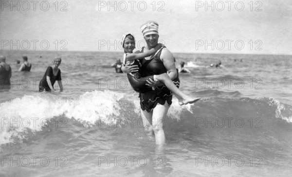 Woman in the water with a child, 1920s, A woman and a child in swimwear smiling in the sea, Historical photo