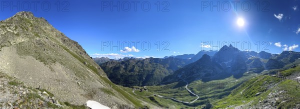 Panoramic view Panoramic photo with sun backlight shot of view of Italian south ramp southern ascent mountain road alpine road to pass in Alps alpine pass above tree line Colle di Gran San Bernardo, Col du Grand Saint Bernard, Great Saint Bernard Pass, Saint-Rhémy-en-Bosses, Italy