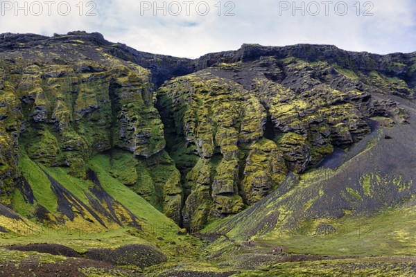 Moss-covered rock formation with entrance to the mystical lava cave, Sönghellir lava tube, Cave of Songs, Arnarstapi, Snaefellsjökull National Park, Snaefellsnes Peninsula, West Iceland, Iceland