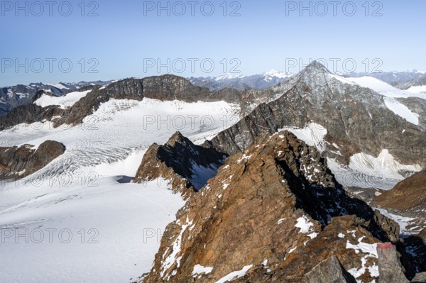 Narrow rocky ridge on the Wilder Freiger summit, picturesque high mountain landscape with snow, view of Übeltalferner glacier and rocky Wilder Pfaff mountain summit, Stubai Alps, South Tyrol, Italy