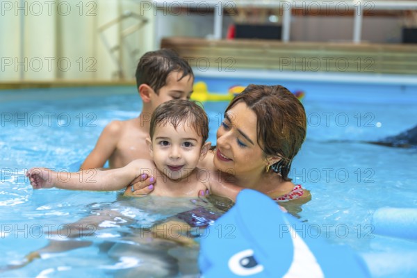 Mother and two sons enjoying time together, playing with inflatable toy in home swimming pool, promoting family bonding and water safety